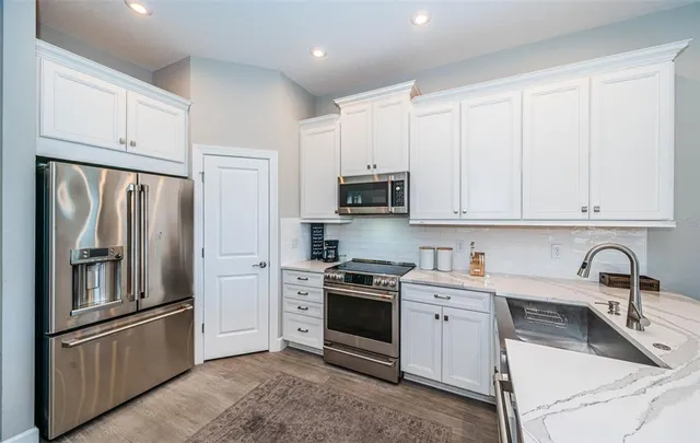 a kitchen with granite countertop white cabinets and stainless steel appliances