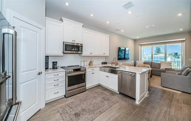 a kitchen with stainless steel appliances granite countertop a stove a sink dishwasher a refrigerator and a microwave oven with wooden floor