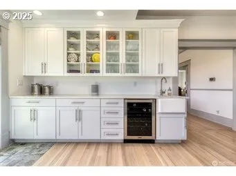 a view of kitchen with granite countertop a stove top oven a sink and white cabinets with wooden floor