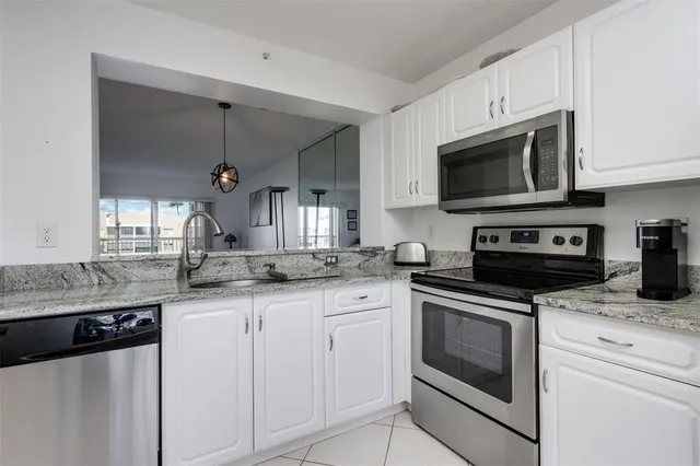 a kitchen with granite countertop white cabinets white stainless steel appliances and a sink