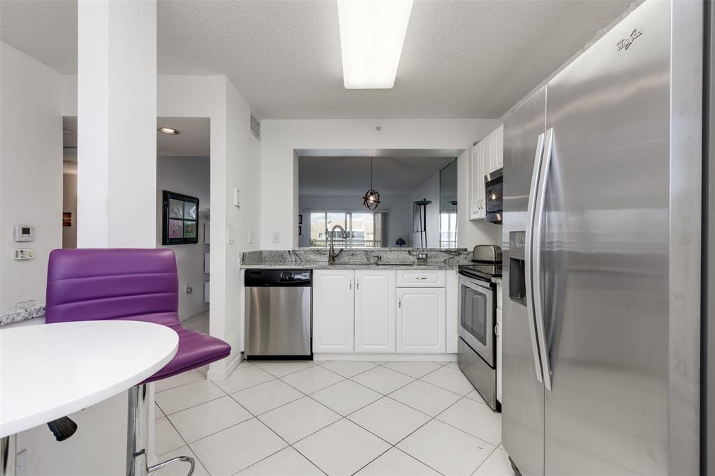 9537 Weldon Circle, Unit 404 Fort Lauderdale, FL 33321 - Photo 19 of 39 a kitchen with stainless steel appliances kitchen island granite countertop a refrigerator and a stove top oven