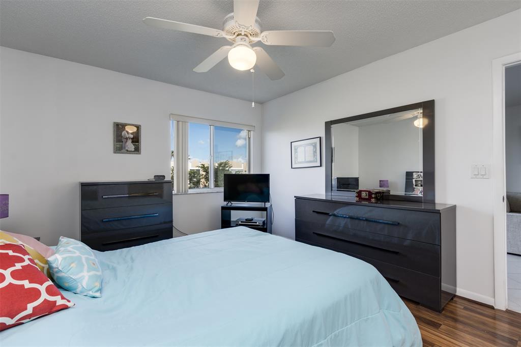 9537 Weldon Circle, Unit 404 Fort Lauderdale, FL 33321 - Photo 20 of 39 a bedroom with a bed and wooden floor