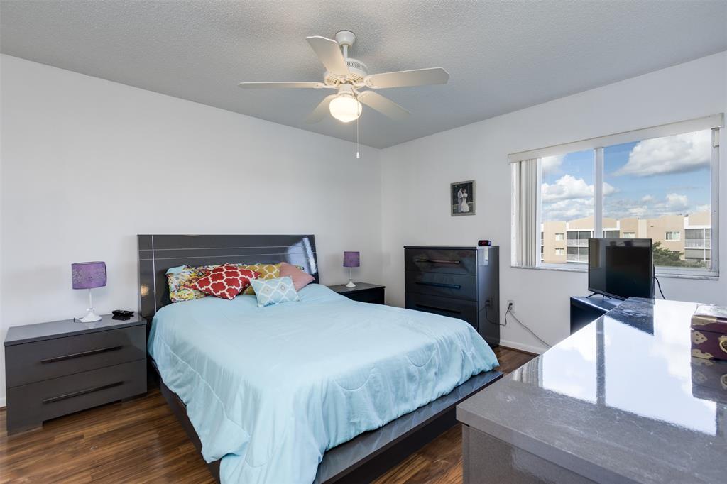 9537 Weldon Circle, Unit 404 Fort Lauderdale, FL 33321 - Photo 22 of 39 a bedroom with a bed and a chandelier