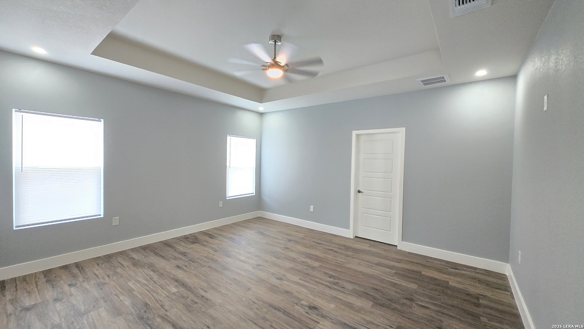 802 Cr 520 D'Hanis, TX 78850 - Photo 32 of 33 an empty room with wooden floor chandelier fan and windows