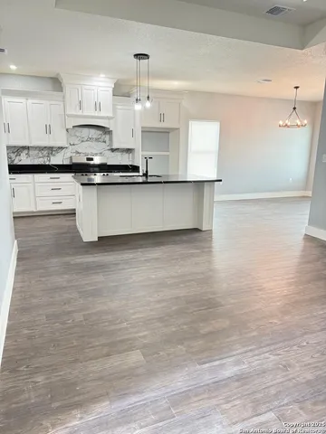 a large kitchen with granite countertop a sink a counter space and cabinets
