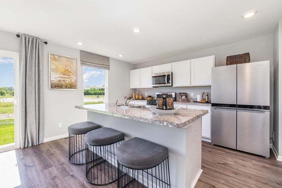 615 Ensign Place Hebron, IN 46341 - Photo 17 of 29 a kitchen with stainless steel appliances granite countertop a refrigerator a stove a sink dishwasher a dining table and chairs with wooden floor