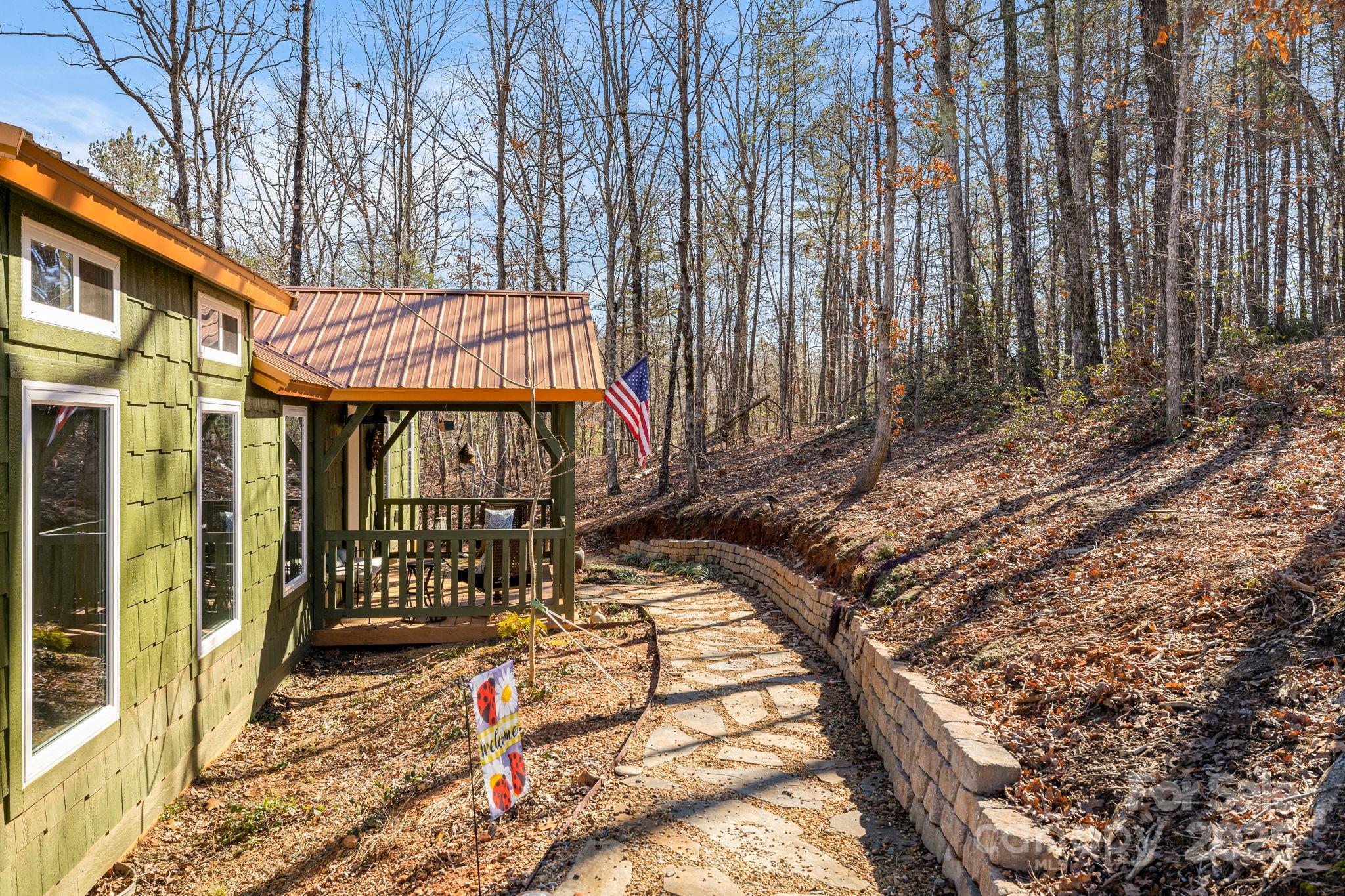 81 Delind Drive Mill Spring, NC 28756 - Photo 5 of 40 a view of a brick house with large trees and wooden fence