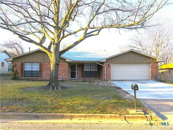 a front view of house with yard and trees in the background
