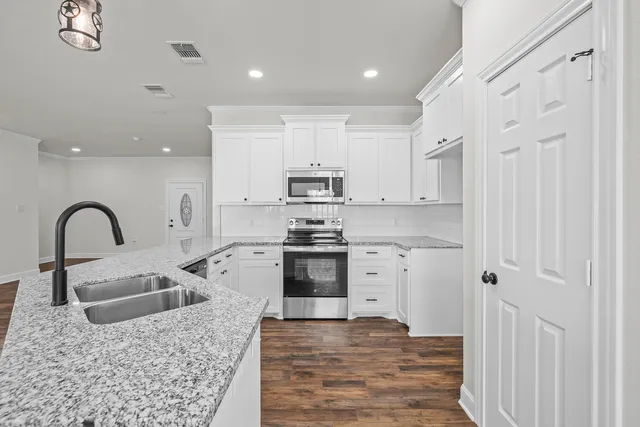 a kitchen with stainless steel appliances granite countertop a sink a stove and a refrigerator