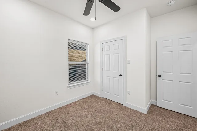 an empty room with windows and fan