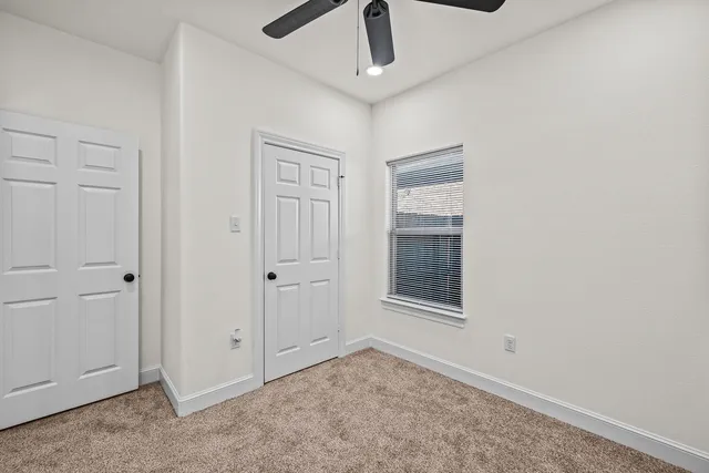 an empty room with a window and a fan