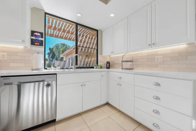 a kitchen with white cabinets and a window