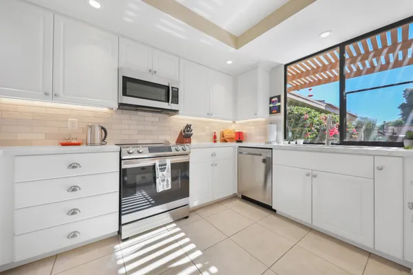 a kitchen with white cabinets and a window