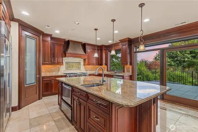a kitchen with stainless steel appliances granite countertop a sink a stove and a wooden cabinets