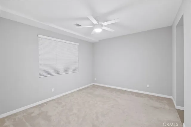 an empty room with a ceiling fan and a window