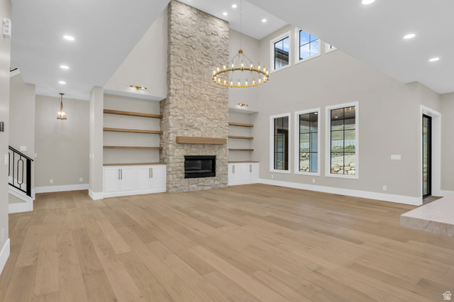 2828 Jojo Road Eagle Mountain, UT 84005 - Photo 7 of 63 Spacious living area featuring a floor-to-ceiling stone fireplace, a gold-finish chandelier, and wood-finish flooring