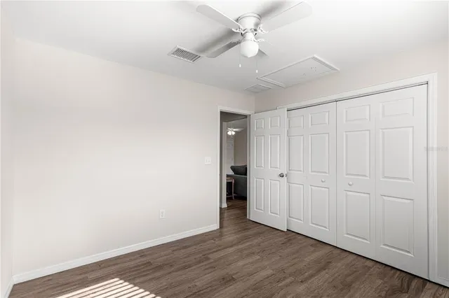 an empty room with wooden floor fan and windows