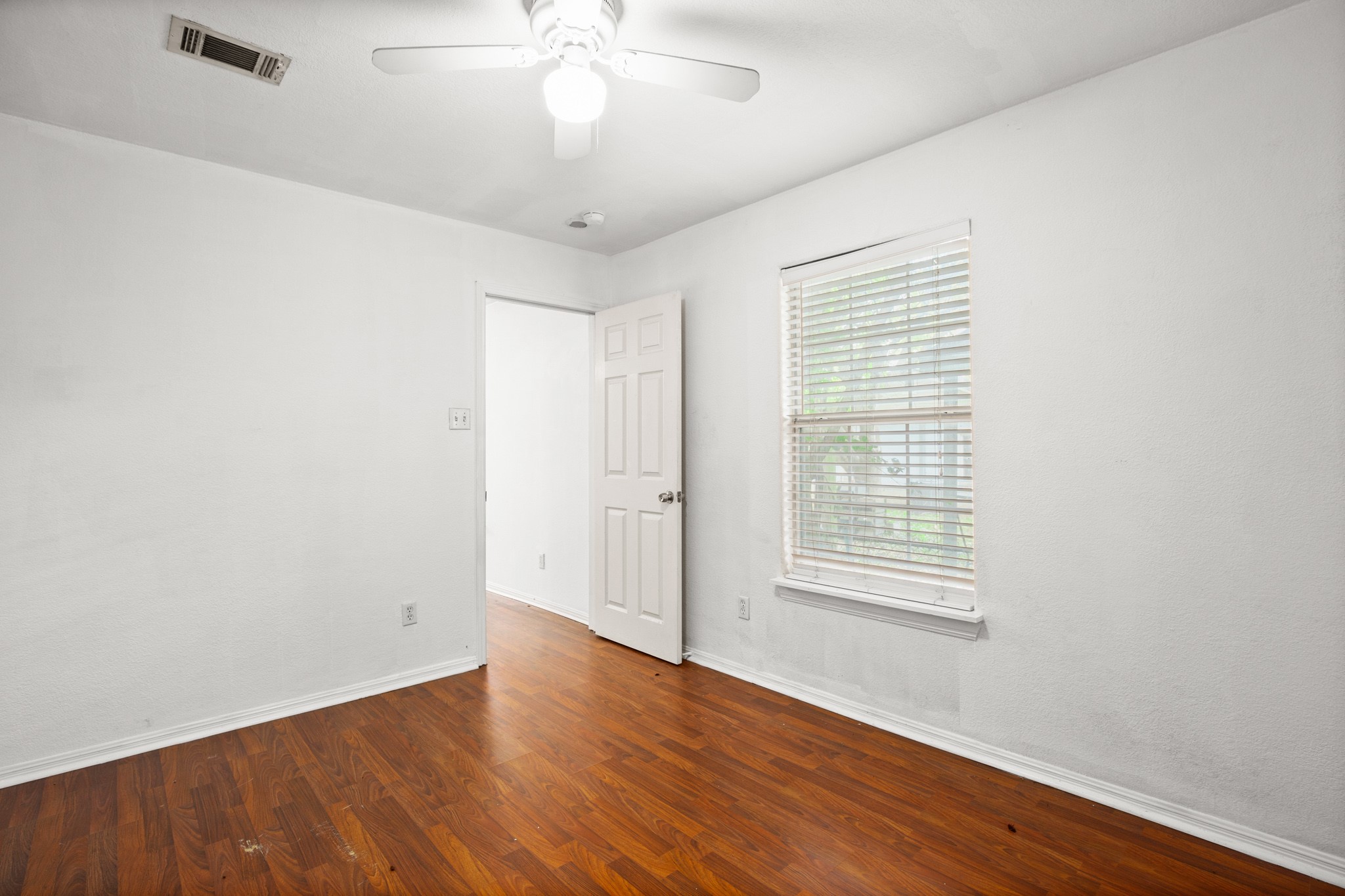 2610 East 3rd Street, Unit B Austin, TX 78702 - Photo 12 of 14 an empty room with wooden floor chandelier fan and windows
