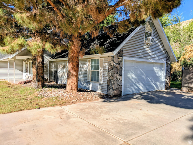 441 Main Street Hurricane, UT 84737 - Photo 28 of 29 Stone facade accents, horizontal siding, attached garage, mature trees, and a concrete driveway