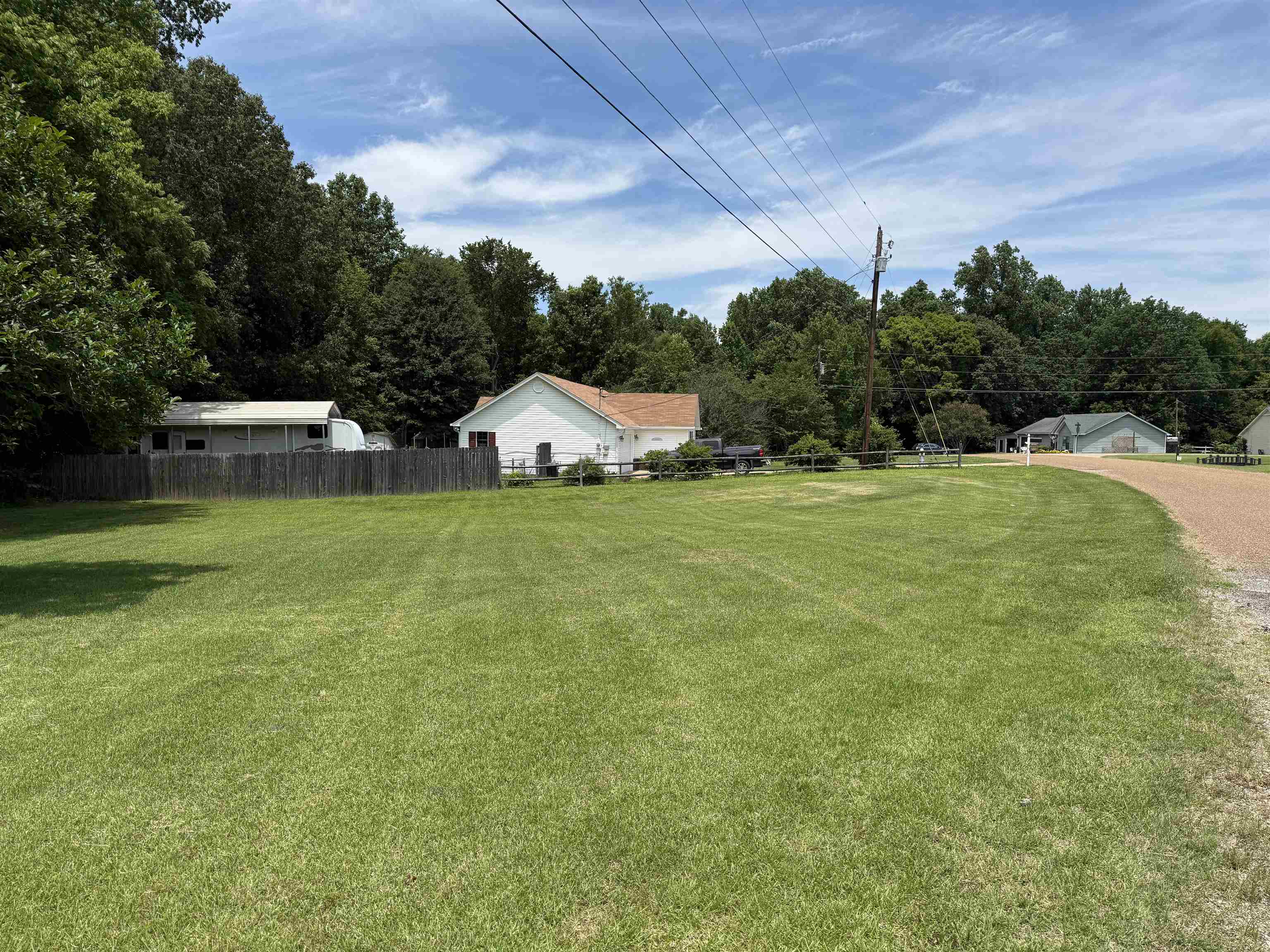 185 Mignon Road Atoka, TN 38004 - Photo 8 of 34 Expansive green lawn with a natural tree line backdrop and a partial wood fence