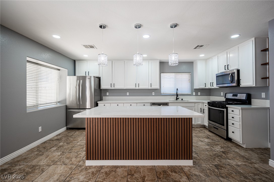 552 Zuber Avenue Henderson, NV 89011 - Photo 3 of 20 Kitchen with stainless steel appliances, pendant lighting, a center island, white cabinetry, and open shelves