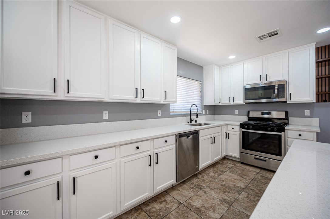 552 Zuber Avenue Henderson, NV 89011 - Photo 4 of 20 Kitchen with appliances with stainless steel finishes, white cabinetry, recessed lighting, and light stone countertops