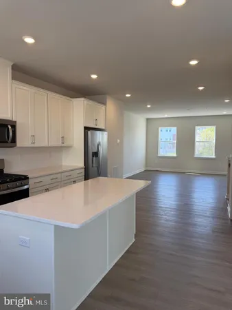 a large kitchen with stainless steel appliances more cabinets and wooden floor