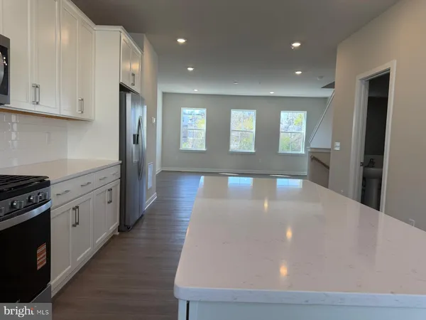 a large kitchen with stainless steel appliances a large counter top a stove and a refrigerator