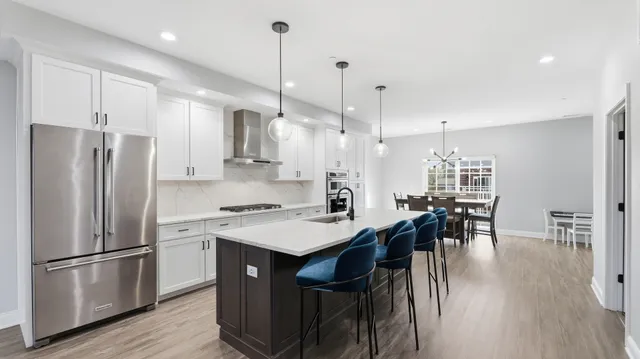 a kitchen with stainless steel appliances a dining table chairs stove refrigerator and wooden floor