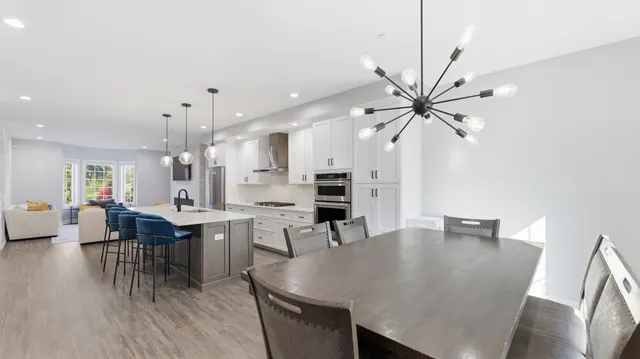 a dining hall with stainless steel appliances kitchen island granite countertop a dining table chairs and a refrigerator