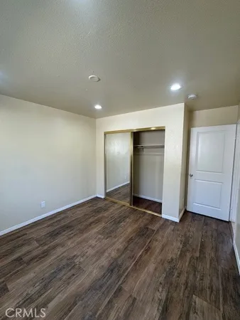a view of an empty room with wooden floor and closet