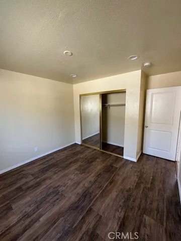 a view of an empty room with wooden floor and closet