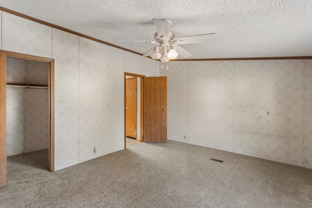a view of an empty room with a chandelier fan
