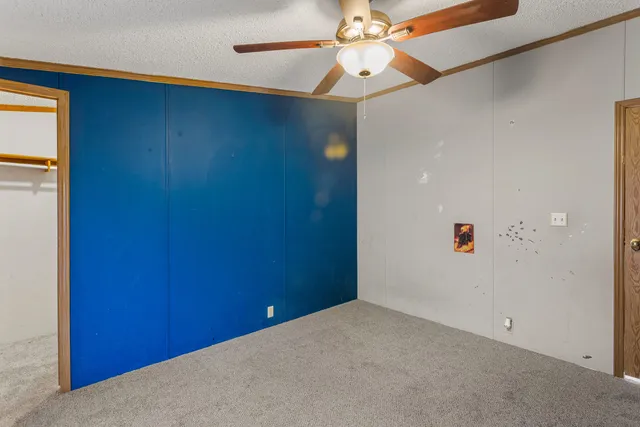 an empty room with a fan & a ceiling fan