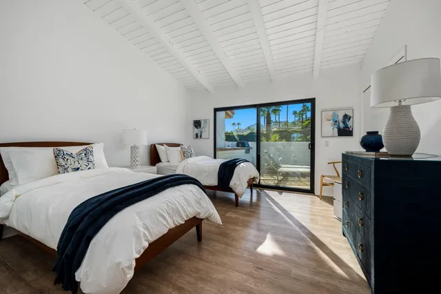 a bedroom with two beds and large windows