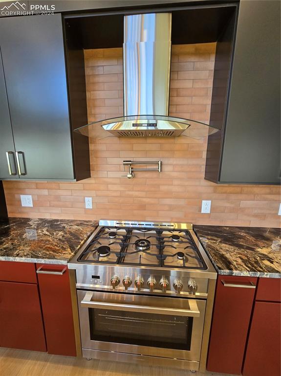 33036 Meadow Ridge Lane Trinidad, CO 81082 - Photo 23 of 50 Kitchen featuring dark stone countertops, exhaust hood, decorative backsplash, and stainless steel range oven