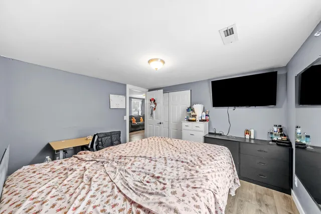 a bedroom with a bed and a flat tv screen on the dresser