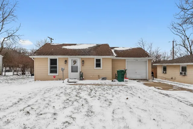 a front view of a house with a dirt yard and a large tree
