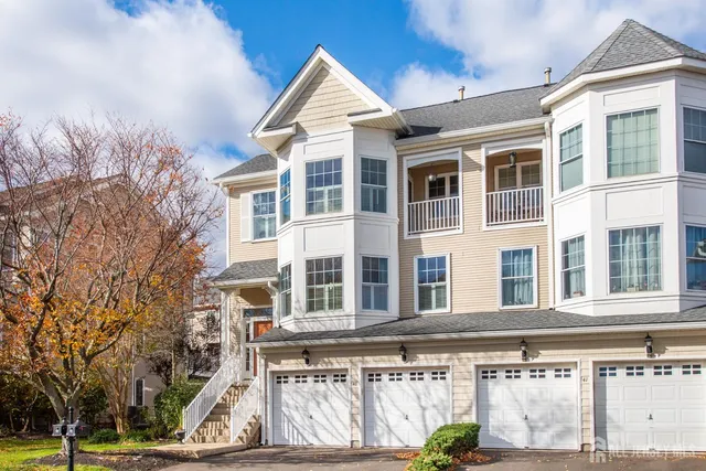 a front view of a building with a garden and trees
