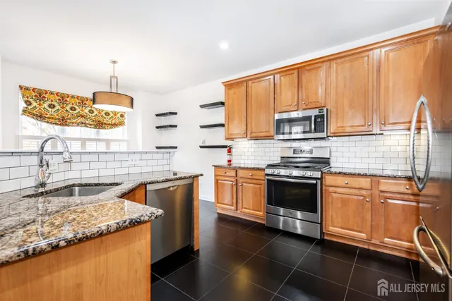 a kitchen with granite countertop a refrigerator and a sink
