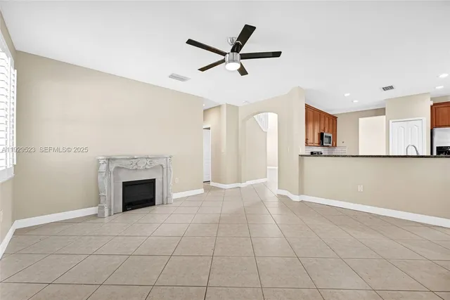 an empty room with wooden floor chandelier fan and windows