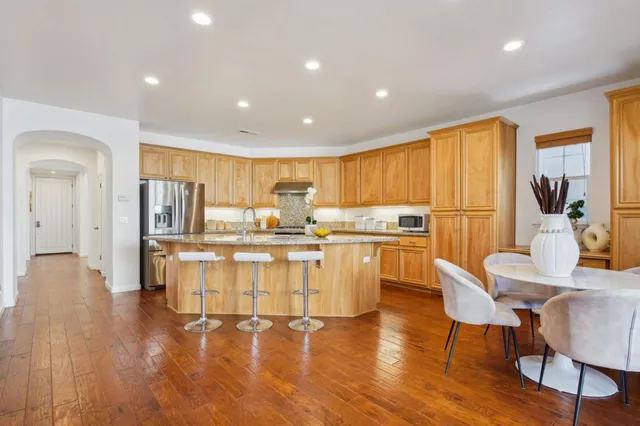 a kitchen with stainless steel appliances granite countertop a refrigerator a stove top oven and a refrigerator with wooden floor