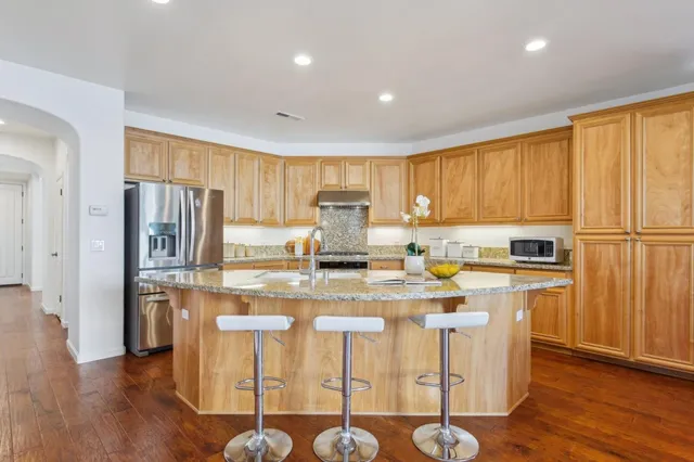 a room with stainless steel appliances granite countertop a sink and a refrigerator