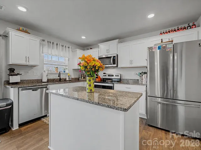 a kitchen with stainless steel appliances granite countertop a refrigerator a sink a stove a microwave and island