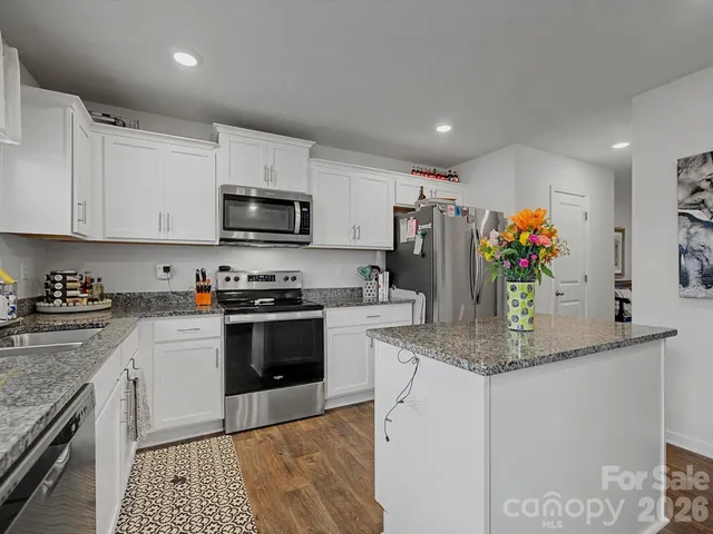 a kitchen with stainless steel appliances granite countertop a sink dishwasher a stove and a refrigerator