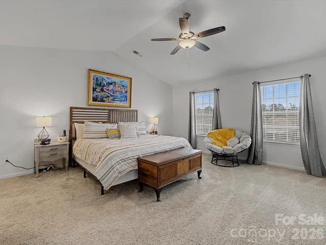 a spacious bedroom that has a bed and a chandelier