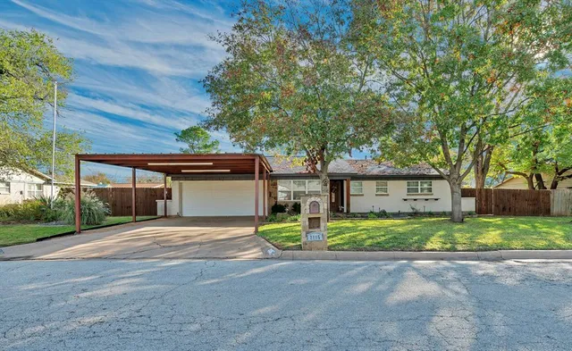 a view of a house with a yard and large tree