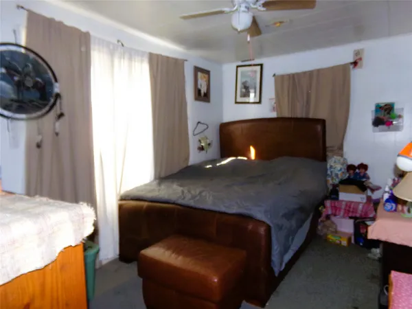a bedroom with a bed a chair and potted plant on the dresser