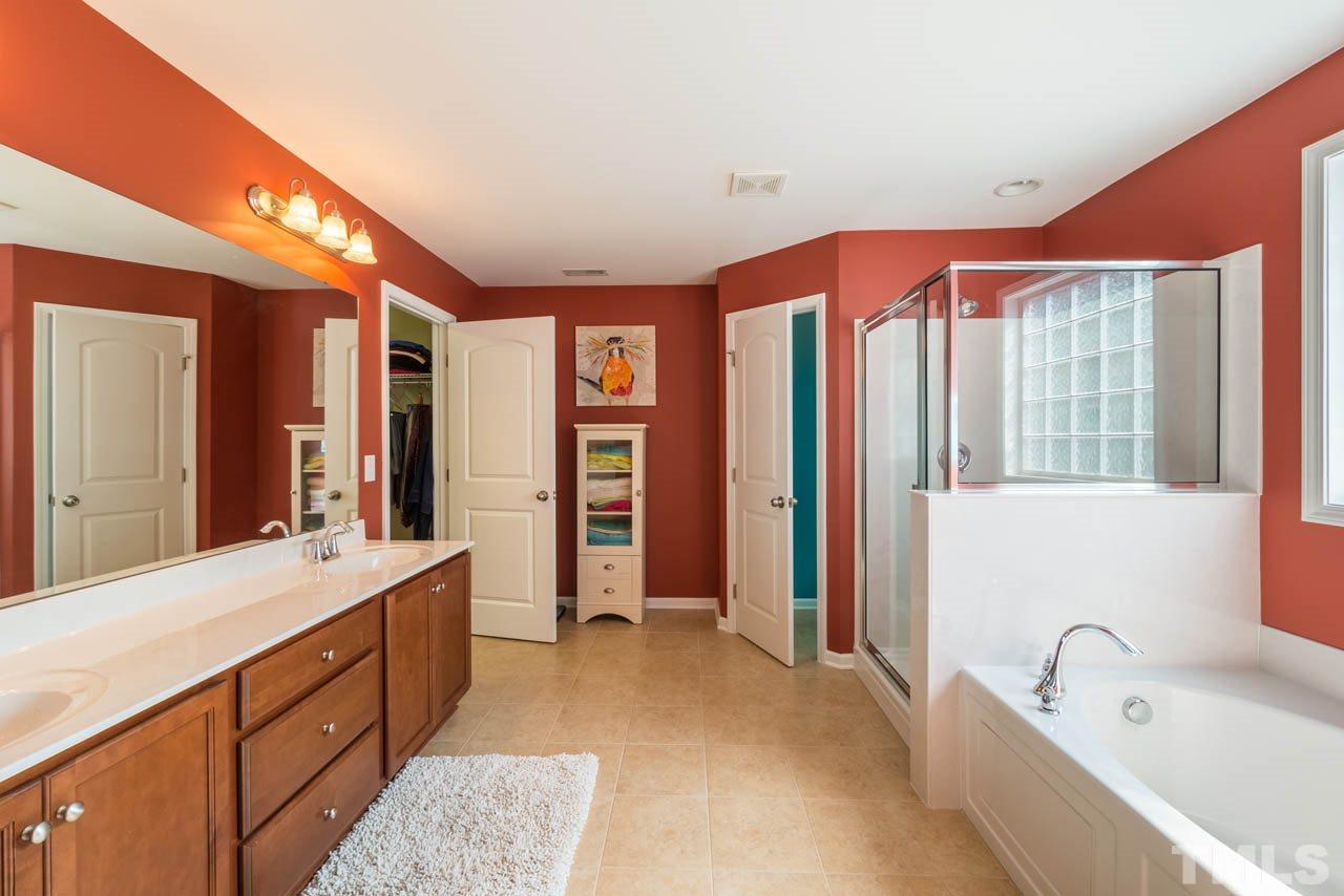 227 Strolling Way Durham, NC 27707 - Photo 15 of 25 a spacious bathroom with a double vanity sink a large mirror and a bathtub