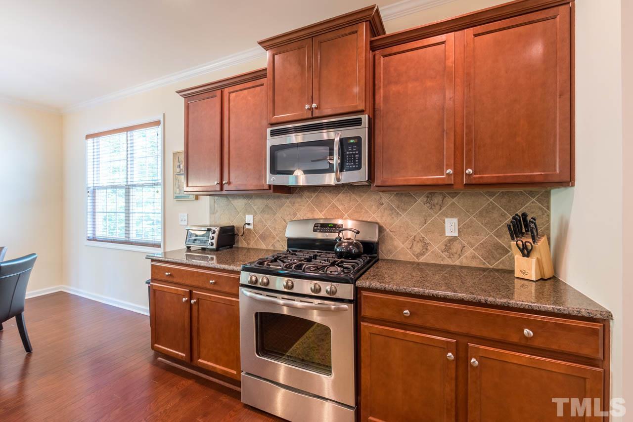 227 Strolling Way Durham, NC 27707 - Photo 9 of 25 a kitchen with granite countertop wooden cabinets and a stove top oven